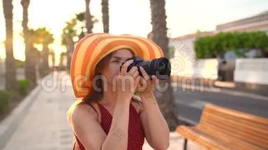 <strong>摄影</strong>女游客戴着一顶黄色的大帽子，在夕阳下美丽的<strong>热带</strong>风景中用相机拍照