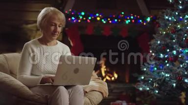 在<strong>圣诞</strong>树附近的<strong>圣诞</strong>夜，老妇人在笔<strong>记</strong>本电脑上发短信
