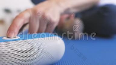 一个<strong>坐在地板上的女人</strong>打开一个便携式蓝牙扬声器，愉快地听音乐。