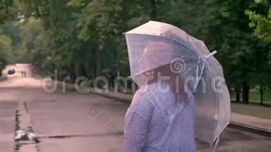 胖姜女的剪影在雨中漫步在公园的路上，转过身，微笑着，撑着伞，回头看