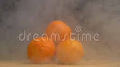 一堆新鲜多汁的橘子，在黑色的背景上旋转，从中吹出凉爽和蒸发，关闭