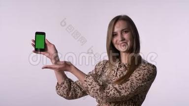 年轻漂亮的<strong>女人</strong>展示了绿色的智能手机屏幕，比如标志，相机<strong>手表</strong>，交流概念，白色