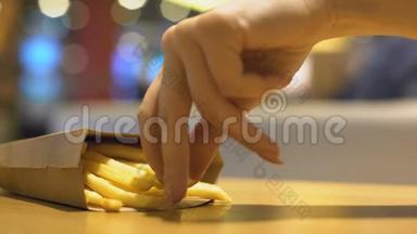 女士的手指在桌子上走来走去，从纸箱里拿着脆脆的炸薯条