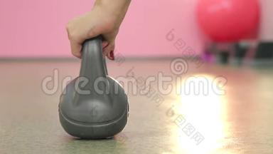 女人`双手特写，在健身房里举起灰色的陀螺来健身