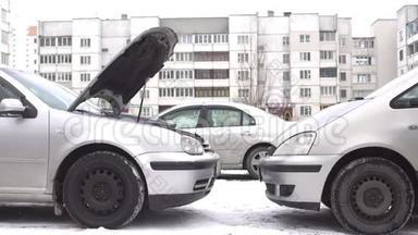 一个男人准备一个汽车捐献者，在冬天用放电电池启动一辆汽车，跳跃启动，蓄能器