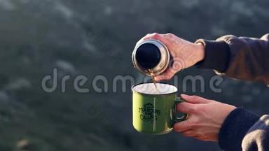 一个女孩的特写镜头`她的手把茶从热水瓶里倒进山里的杯子里