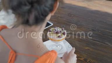 特写镜头，戴眼镜的女人坐在海边的咖啡馆里吃甜点