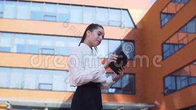 年轻的商业女孩站在商业大厦附近，手里拿着一块平板<strong>电脑</strong>。 高清高清