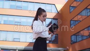 商务女孩站在商务大楼附近，手里拿着一块平板<strong>电脑</strong>。 高清高清