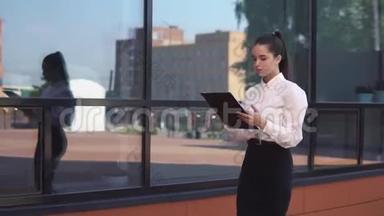 黑发的年轻商务女孩手里拿着文件来到商务中心附近。 高清高清