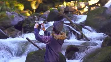 女孩在森林里给一条美丽的山河拍照，慢悠悠的