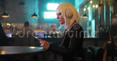 不寻常的女孩戴着白色假发，在酒吧里用耳机听音乐