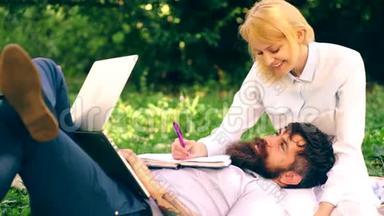 年轻夫妇正在公园里准<strong>备考</strong>试。 有胡子的家伙和一个漂亮的女孩躺在毯子上，拿着笔记本电脑和