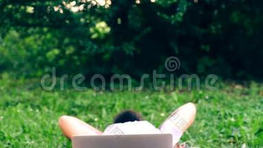那个留胡子的人坐在公园的草地上，用笔记本电脑工作。 理念的产生.. 学生是