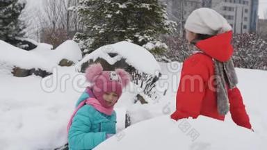 孩子们在冬天玩雪球。 两个姐妹塑造雪球，扔给你的朋友。