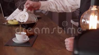 男人用手从吧台上的水壶里倒咖啡