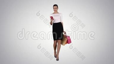 快乐的年轻女子与智能<strong>手机制作</strong>照片，她的购物袋在梯度背景。