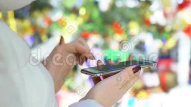 特写镜头。在购物中心拿着智能手机的女人的手。圣诞节。太阳光斑的反射