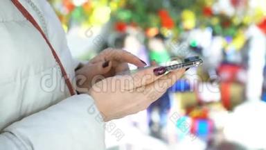 特写镜头。在购物中心拿着智能手机的女人的手。圣诞节。太阳<strong>光斑</strong>的反射
