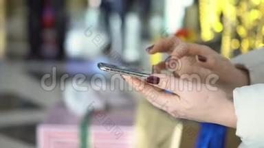 特写<strong>镜头</strong>。在购物中心拿着智能手机的女人的手。圣诞节。太阳<strong>光斑</strong>的反射