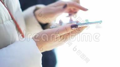 特写镜头。在购物中心拿着智能手机的女人的手。圣诞节。太阳光斑的反射