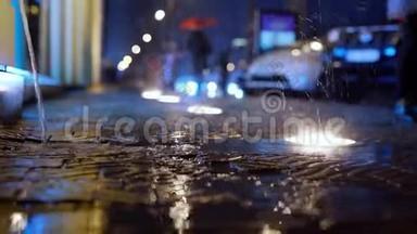 雨在缓慢的运动中落在城市街道上，夜间有地面灯光。