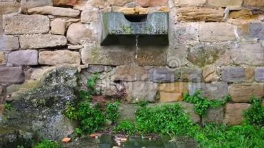 水从一条刻在石头上的水道里滴出来，被困在一堵旧的砖墙里，