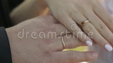 新郎新娘的手。 瓢虫慢慢地爬过新娘的结婚戒指和订婚戒指。 慢动作