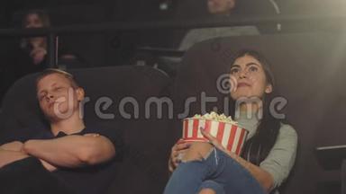 一个年轻人在电影院里看电影时睡着了，而他的女孩则热情地继续看电影