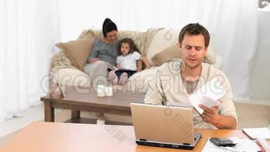 担心的男人一边给女儿读书一边计算账单