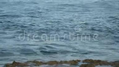 泡沫海浪冲刷岩石海岸. 在塞浦路斯沿海的一个夏天，海浪很小。