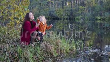 母亲和孩子坐着，在湖边聊天，拥抱着秋天的风景