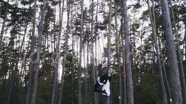 年轻夫妇在美丽的松树的背景下在森林里跳舞。 异族<strong>舞蹈情侣</strong>相爱。 他就是