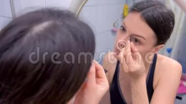 美丽的黑发女人在镜子前的浴室里<strong>画眉</strong>毛。