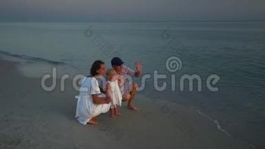 家人在海滩上散步。 <strong>父母</strong>和他们的小女儿沿着海滨散步。 <strong>父母</strong>蹲在他们身边