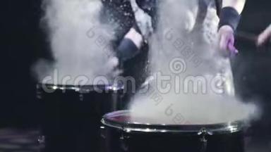 鼓手在鼓上敲打棍子。 行动。 鼓手在大鼓上敲击棍棒，造成白色的飞溅