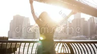 快乐兴奋<strong>嬉戏</strong>的年轻女子用抬起的手臂在河堤围栏附近旋转，微笑着看着镜头缓慢的动作。