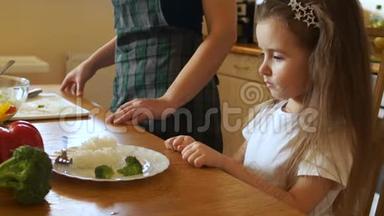 女孩果断地推开了一盘食物。 看着母亲摇摇头，孩子拒绝吃东西