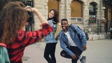 有创意的女孩和男人的朋友正在摆姿势拍照，站在街上，而带背包的年轻女人正在拍照