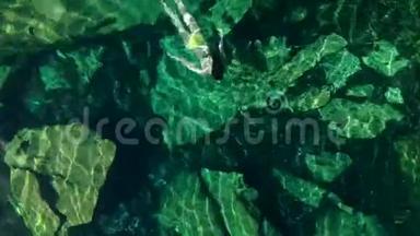 年轻的黑发女人在墨西哥的一个自然的塞诺特游泳池里漂浮和玩耍。