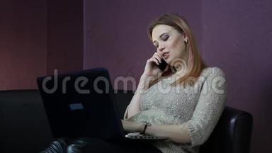 一个年轻的女人坐在一张小沙发上在电脑前工作。