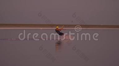 一个戴着照相机的黄色头盔的人在平静的湖面上控制着一只训练风筝
