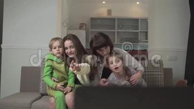 一家人坐在客房的沙发上看电视。 姐姐和弟弟妹妹在一起
