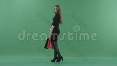 美丽快乐的女人穿着小<strong>黑裙子</strong>，摆着购物袋。 她站在一间工作室里反对