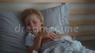 一个带体温计的生病的小男孩在床上被超慢镜头拍摄。 婴儿流感概念