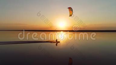 一个孤独的放风筝的人在一个湖上的橙色日落