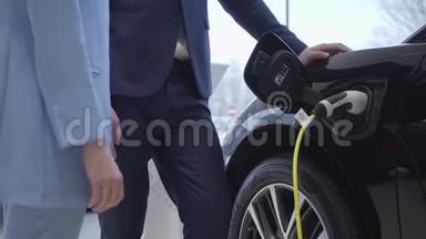 老人正在给一辆电动车插上电源线. 不可辨认的职业推销员站在附近收费