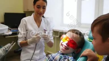 一位年轻的女牙医<strong>正在准备</strong>治疗牙齿。 病人和他的孪生兄弟<strong>正在</strong>微笑