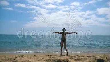 一个面目全非的年轻女子在沙滩上向大海<strong>跑</strong>去，举起手来。美丽的女孩在沙滩上慢<strong>跑到</strong>