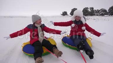 快乐的孩子们在冬天的<strong>雪地</strong>里雪橇，挥舞着他们的手。 孩子们在<strong>雪地</strong>上滑在管子上，欢笑和欢乐